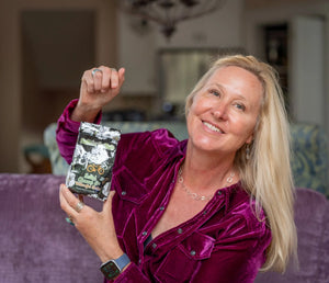 Woman holding Salted Almond & Arnica bath salts package with floral design.