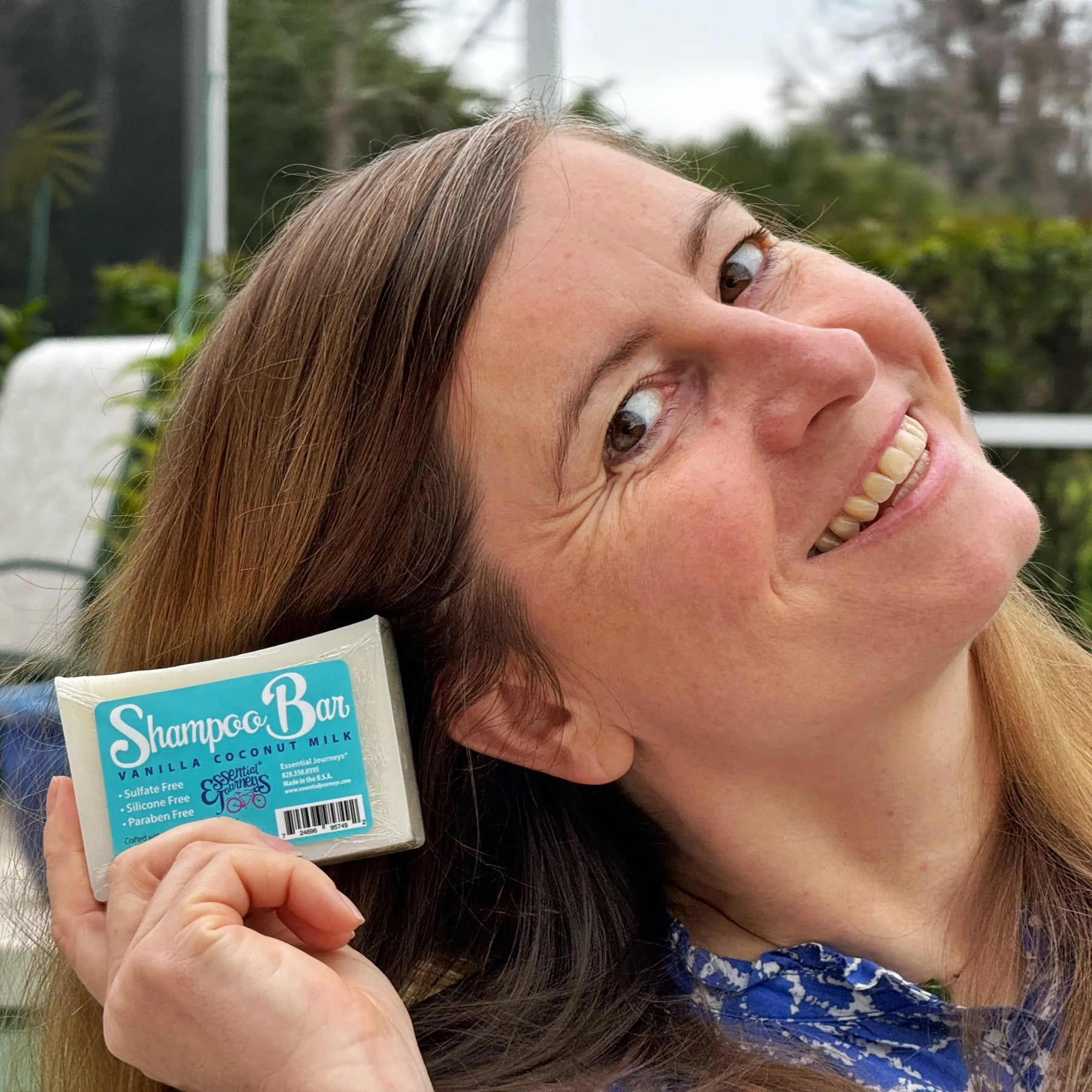 Woman holding vanilla coconut milk shampoo bar with product label visible.