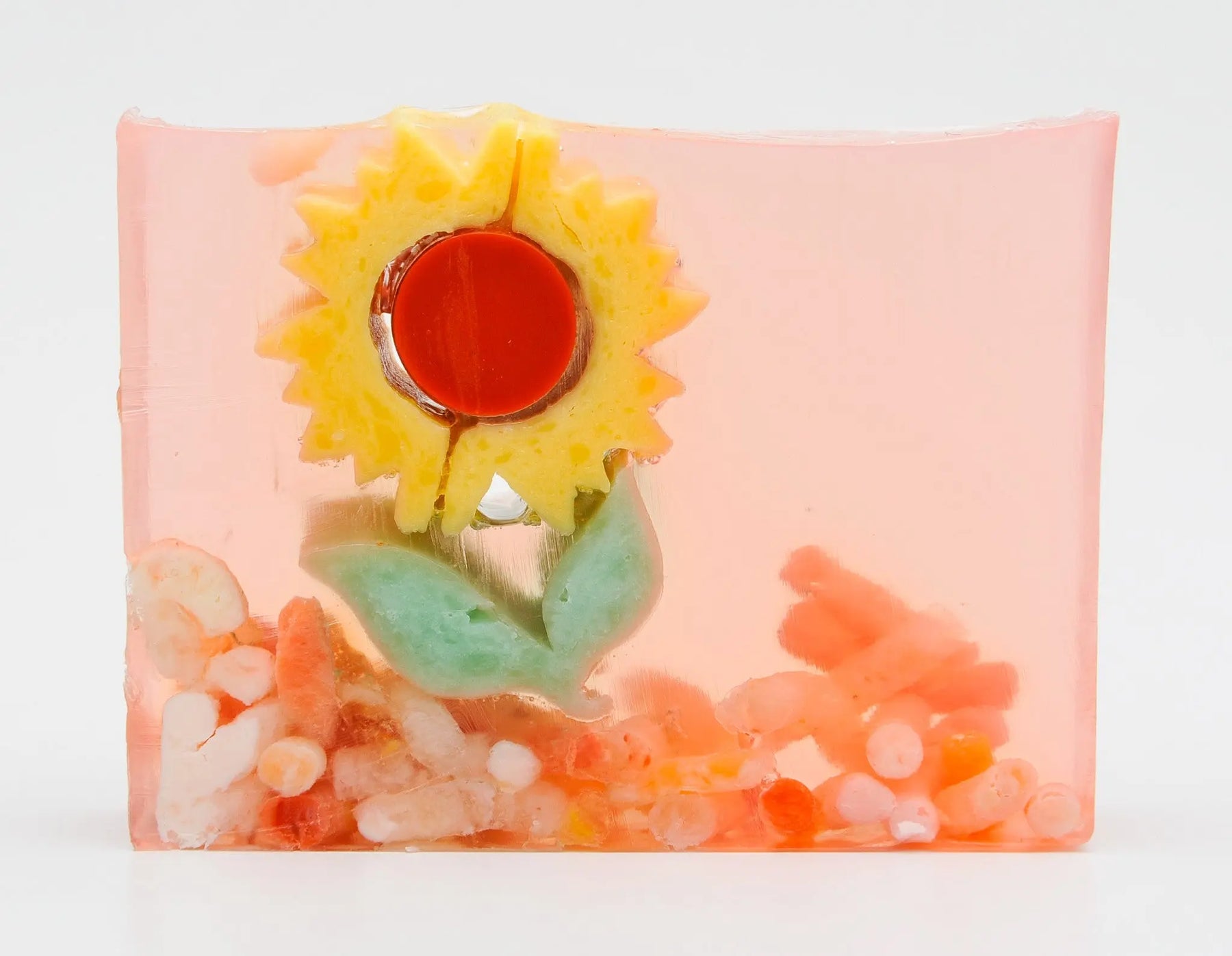 Clear slice soap with a yellow sunflower design and colorful inclusions.