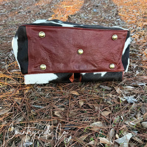Saddlemen carry all cowhide duffle travel bag with rust-red leather base and brass feet.