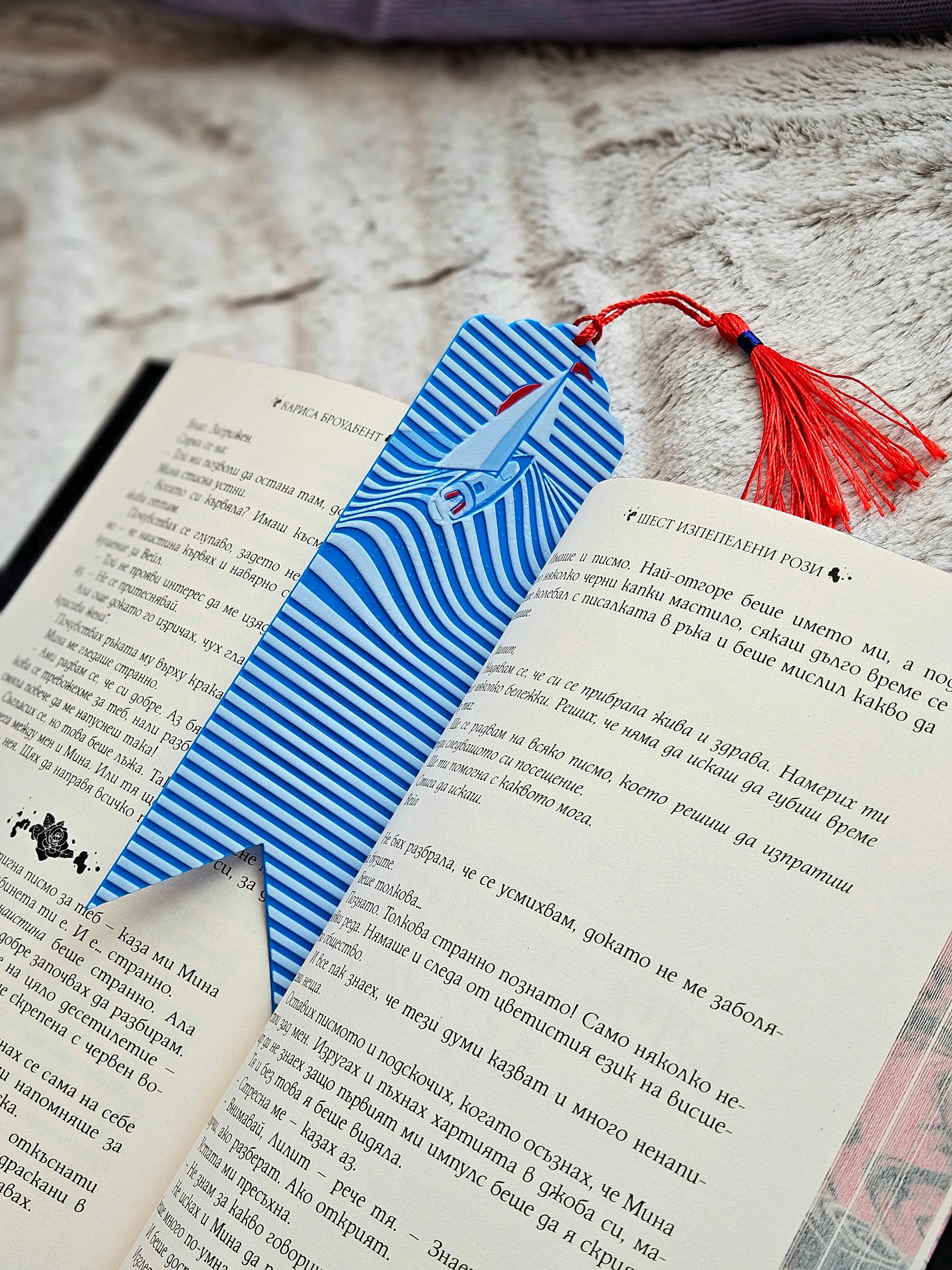 Nautical bookmark featuring a sailboat over blue ocean wave design with a red tassel.
