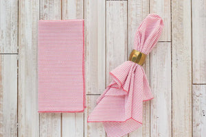 Red and white striped seersucker dinner napkin folded and with a gold napkin ring