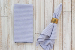 Blue and white striped seersucker dinner napkins folded and on a napkin ring