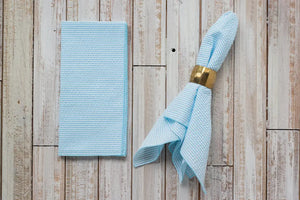 Light blue seersucker napkins folded and draped on a rustic wooden background.