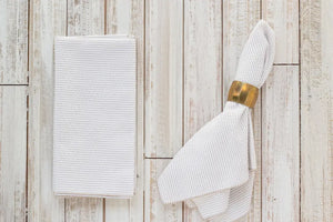 White seersucker cloth dinner napkins on a light wood background.