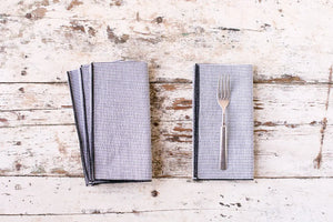 Set of four blue and white striped seersucker dinner napkins with a silver fork