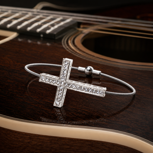 Silver rhinestone cross bracelet on guitar