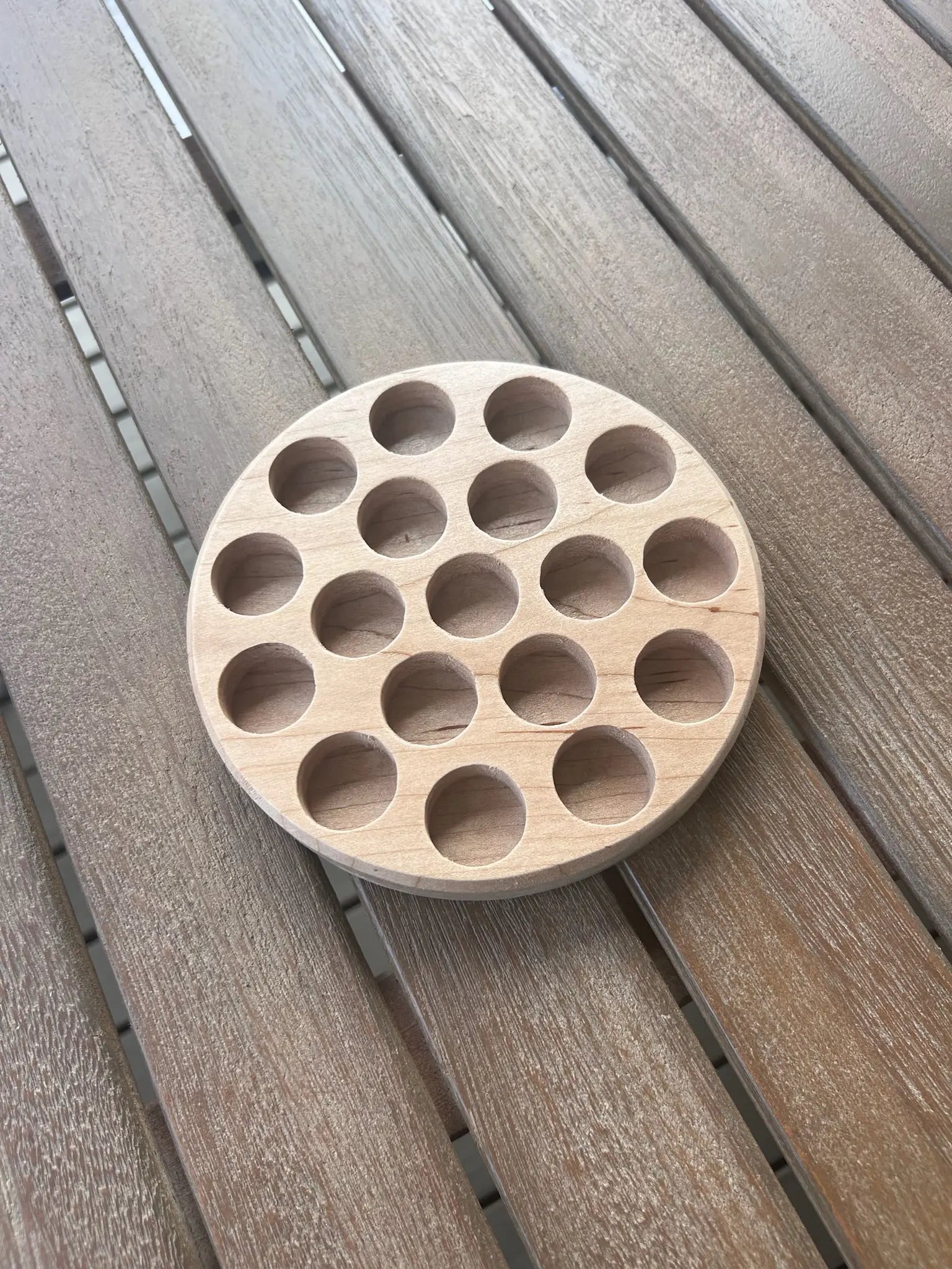 Round wooden tray with 20 holes for storing small toys.