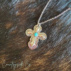 Southwestern cross necklace with turquoise stone on fur background