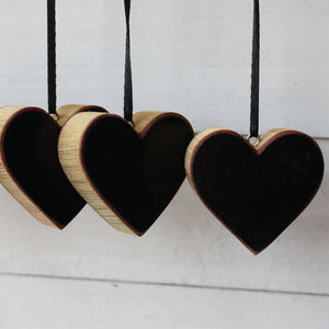 Three wooden heart ornaments with black centers, hanging by black ribbons.