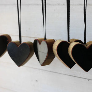 Row of wooden heart ornaments with black centers and black ribbon hangers.