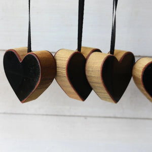 Wooden heart ornaments with black interiors hanging on black ribbon.