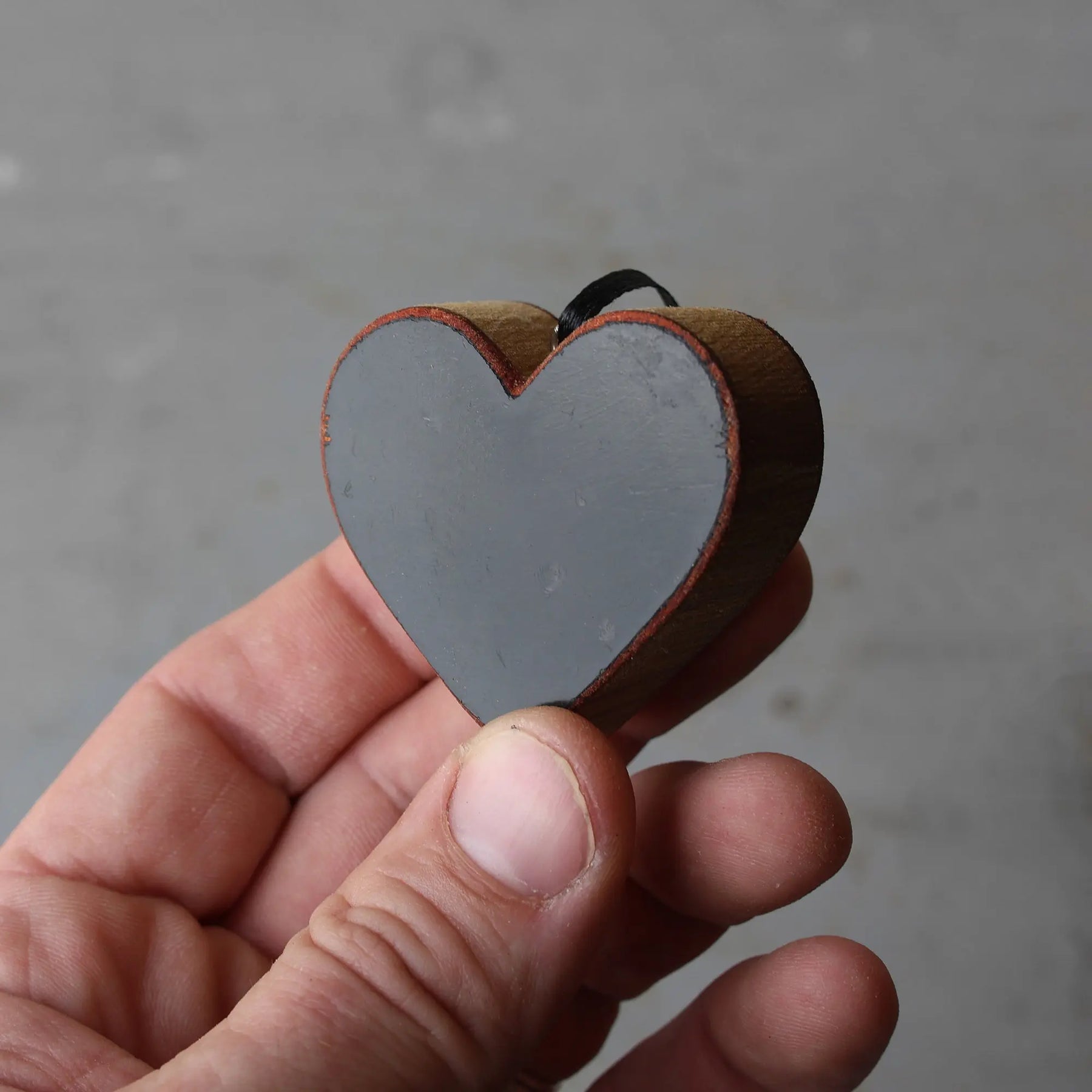 Steinway piano ornament, a grey wooden heart held in a hand.