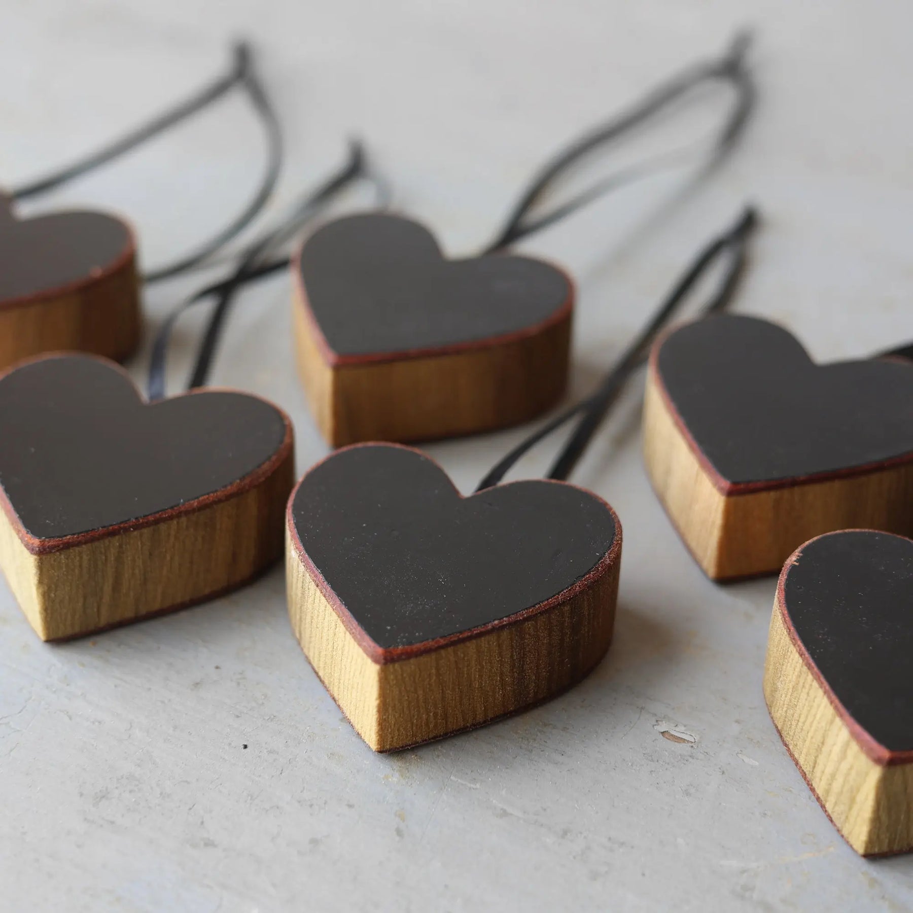 Wooden heart ornaments with black surfaces and black ribbon hangers.