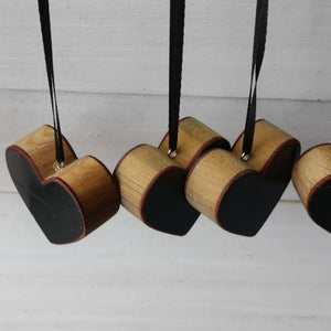 Wooden heart ornaments made from Steinway piano wood with black and natural finishes, hanging on black ribbons.