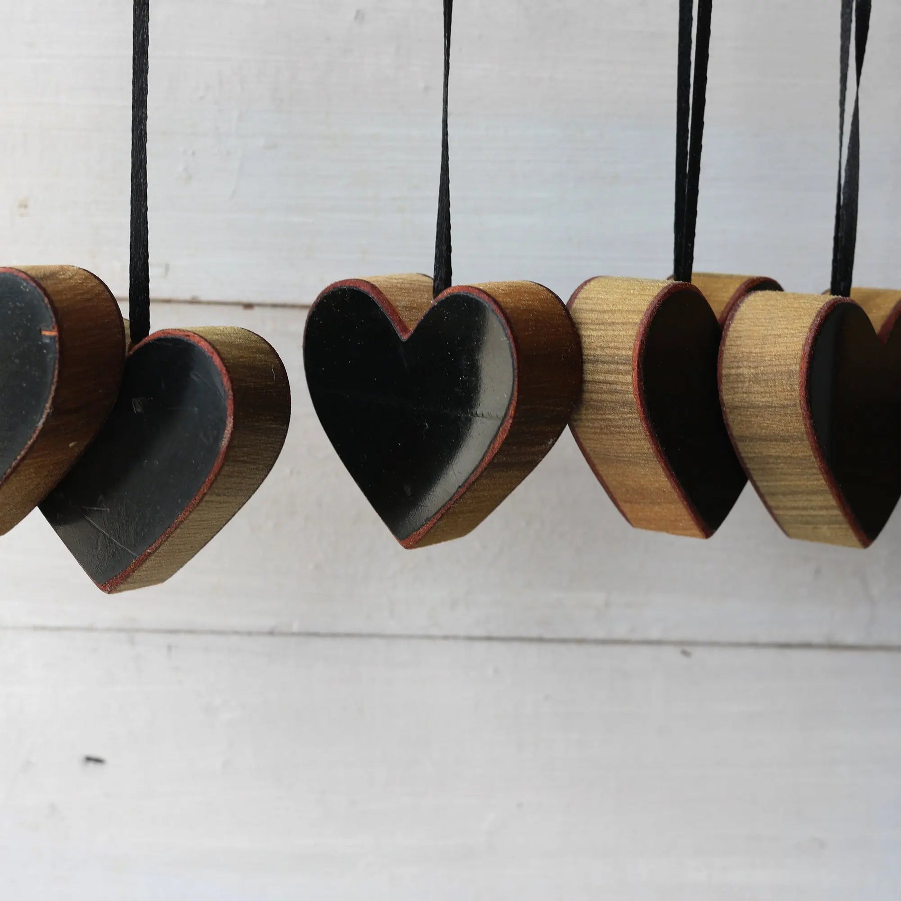 Steinway Piano Heart Ornaments made of wood with black centers and ribbon hangers.