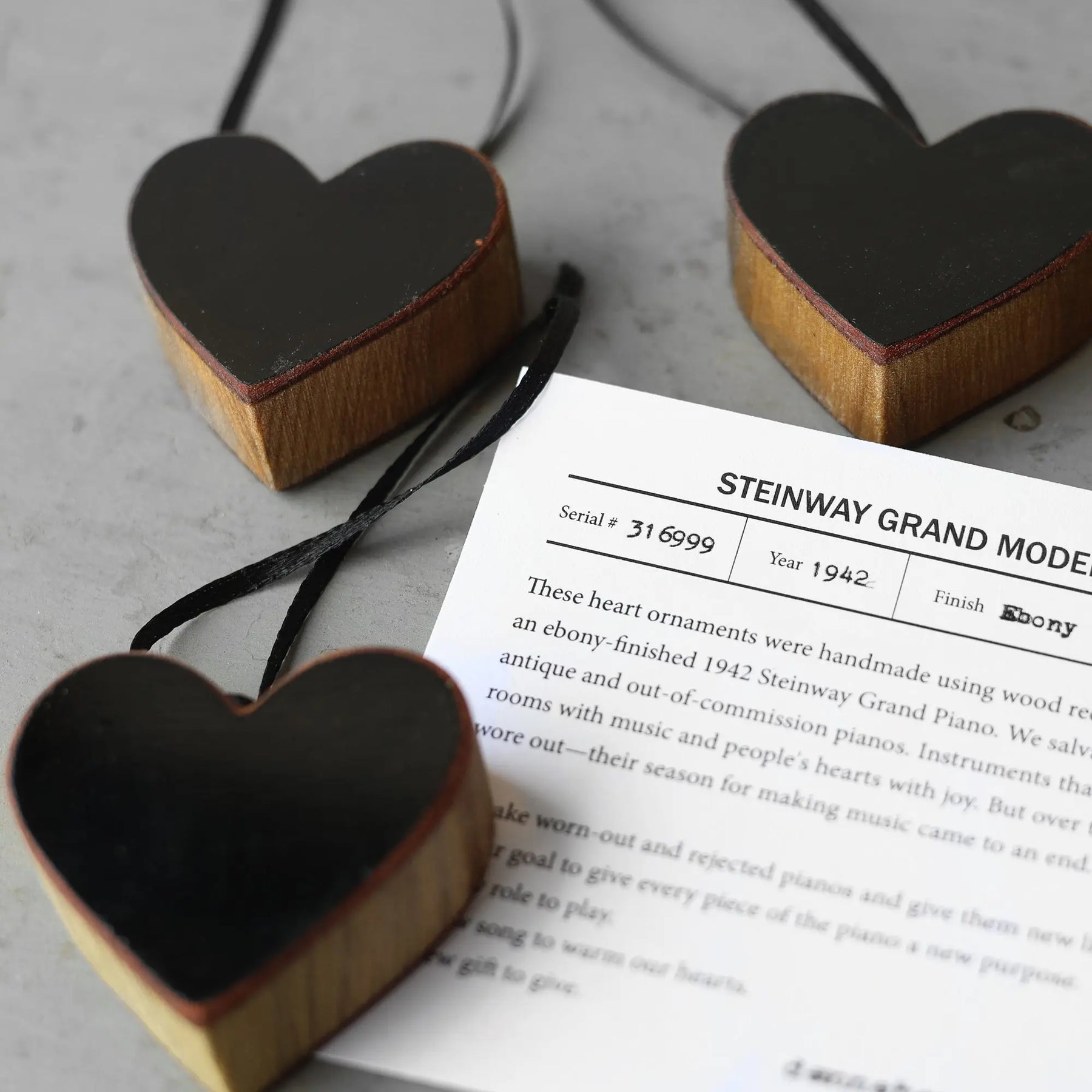 Heart-shaped wood ornaments with black finish and a visible serial number tag.