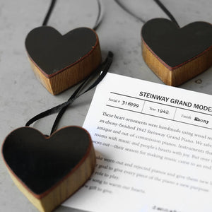 Heart-shaped wood ornaments with black finish and a visible serial number tag.