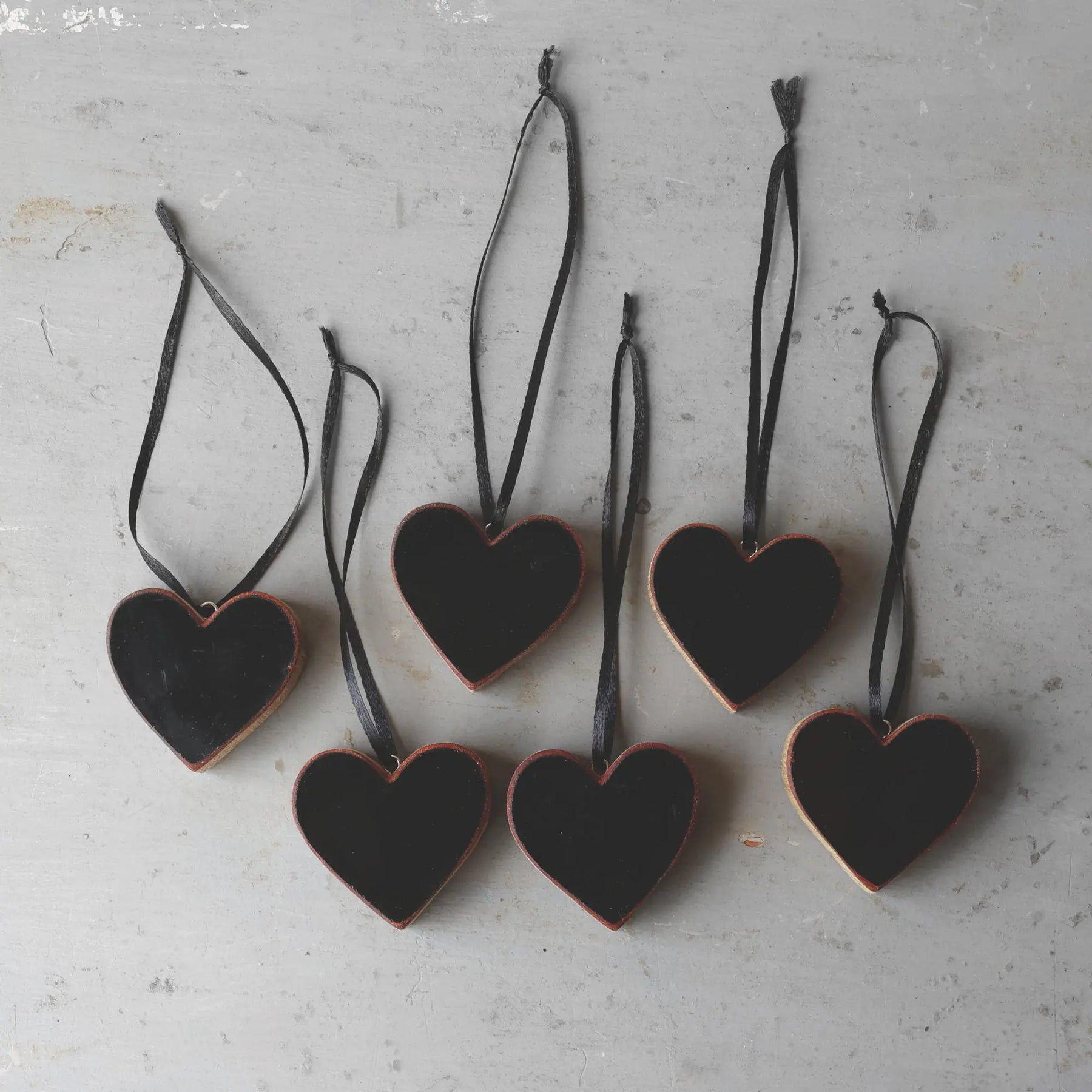 Black heart-shaped ornaments made from reclaimed Steinway piano wood hanging by ribbons.