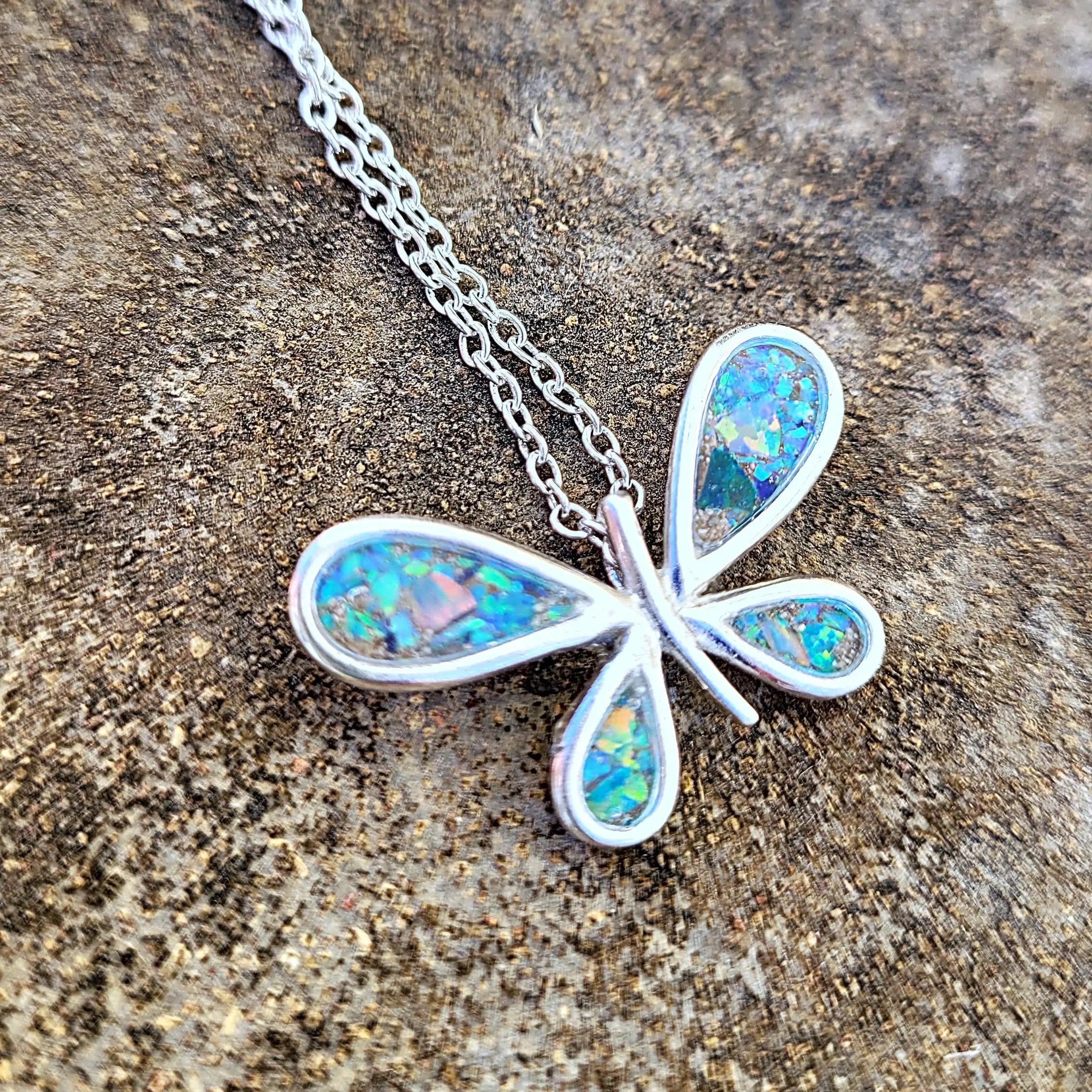 Sterling silver butterfly pendant made with ashes on a chain. Jewelry has blue and green iridescent tones. Cremation keepsake jewelry.