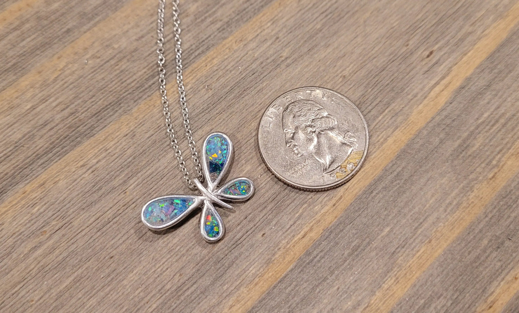 Sterling silver butterfly pendant with colorful inlay next to a U.S. quarter for scale.