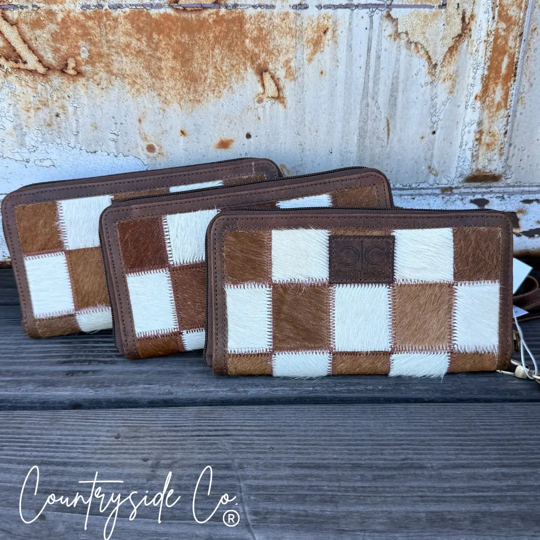Brown and white checkered cowhide wallet with zipper closure.