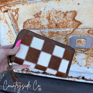 Brown and white checkerboard cowhide wallet with zipper and wristlet.