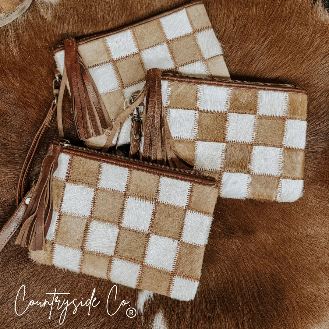 Three checkered cowhide wristlet pouches with leather fringe tassels.