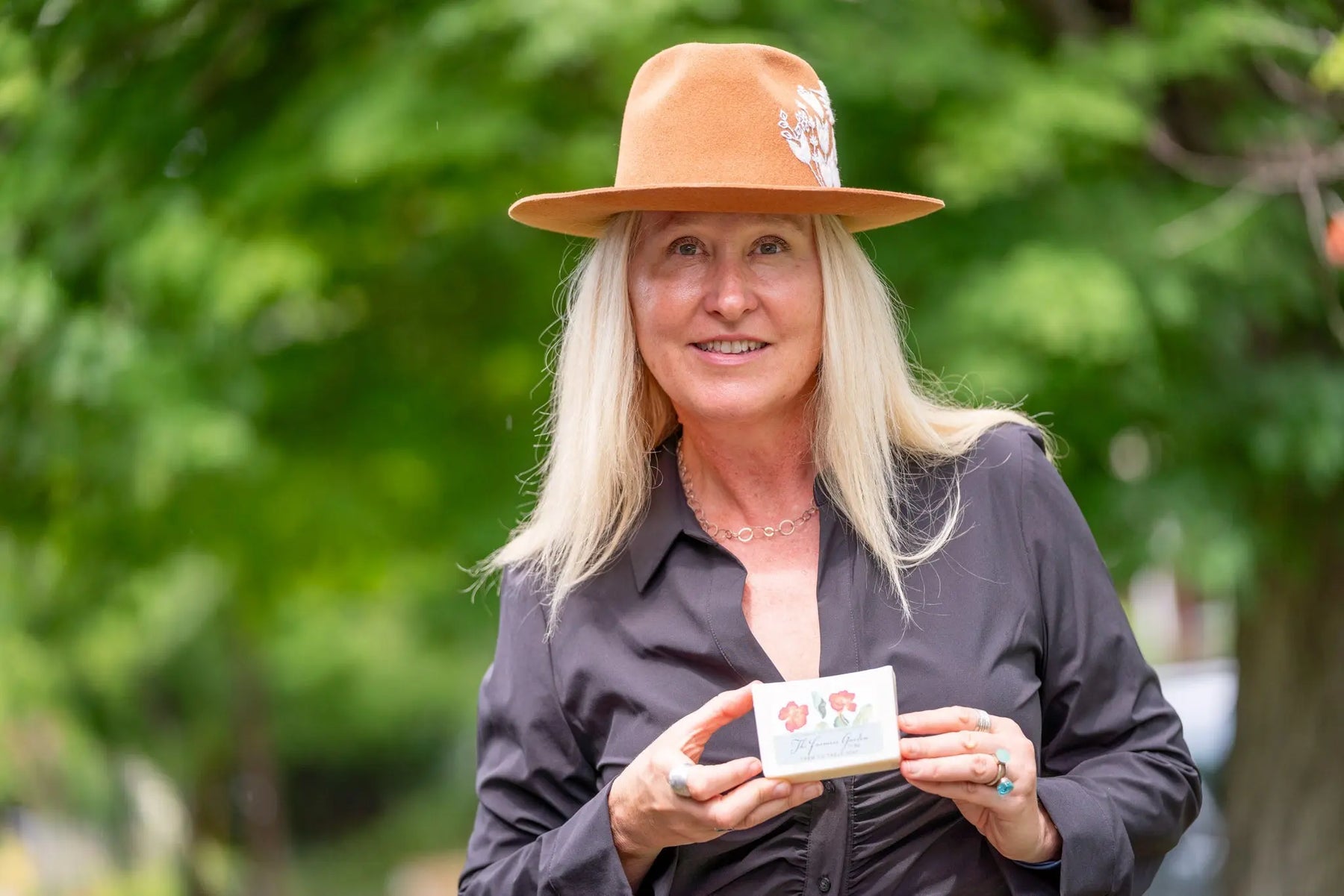 Woman in a hat holding a "The Farmers Garden" 5 oz. farm to table soap slice from Main Street Collective.