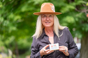 Woman in a hat holding a "The Farmers Garden" 5 oz. farm to table soap slice from Main Street Collective.