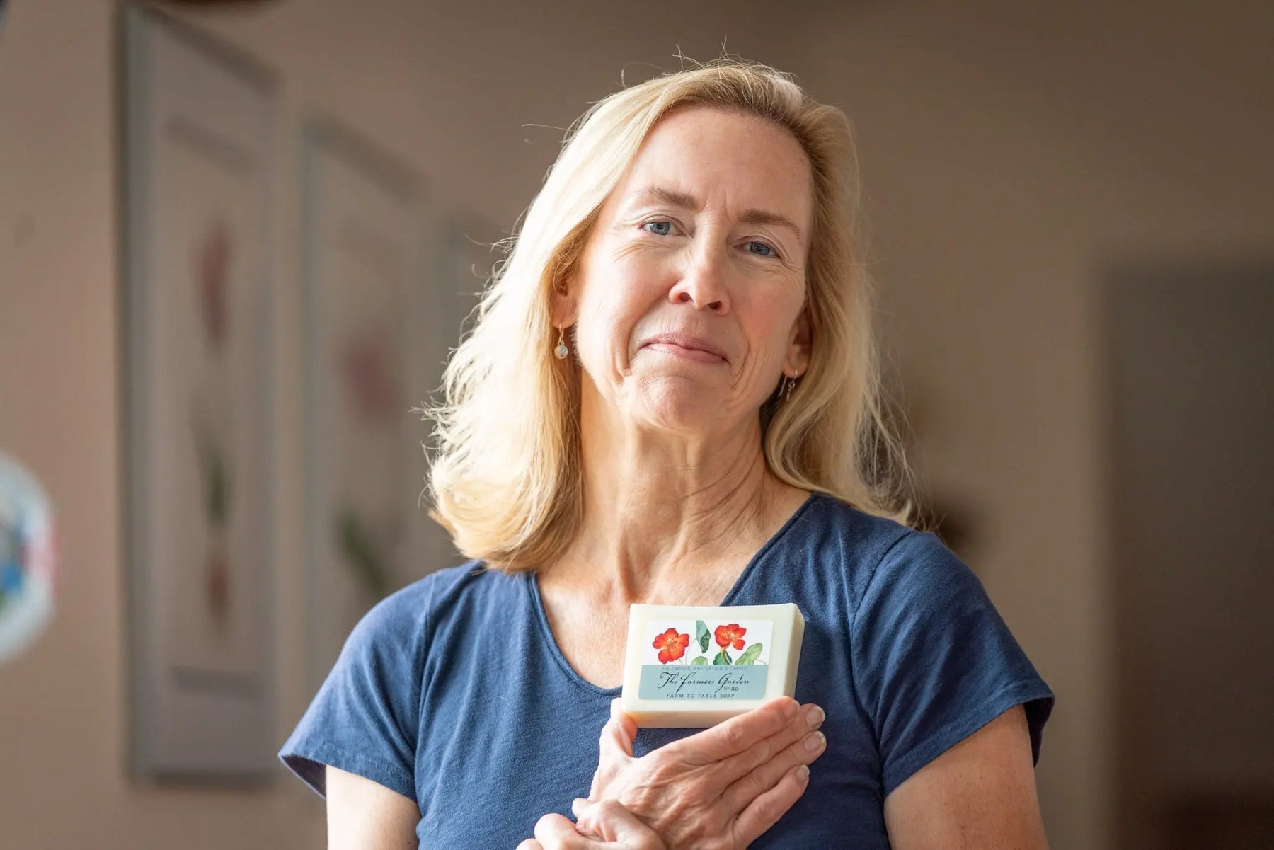 Woman holding a bar of The Farmers Garden 5 oz. Farm to Table Soap with floral label.