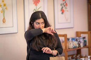 Woman smelling her hand while holding a brown paper bag.
