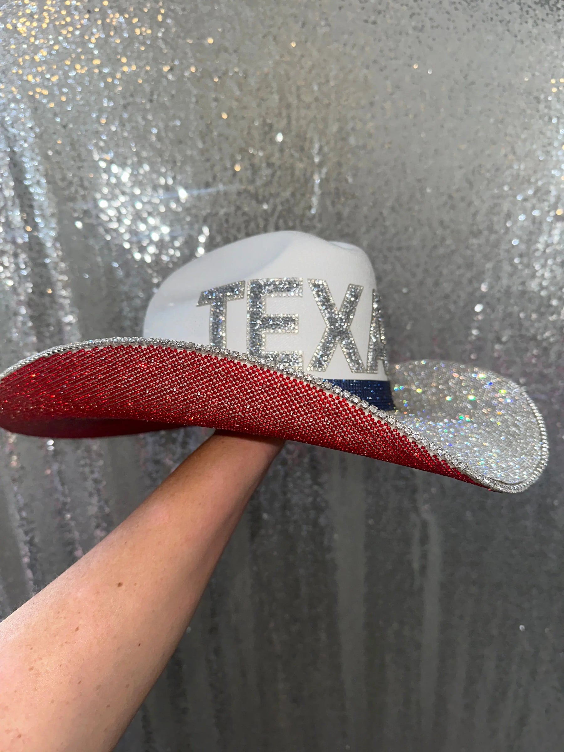 White straw cowboy hat with red, white, and blue rhinestones and "TEXAS" letters.