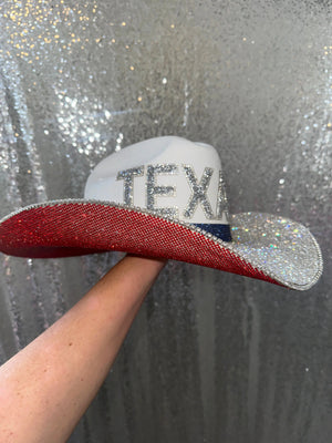 White straw cowboy hat with red, white, and blue rhinestones and "TEXAS" letters.