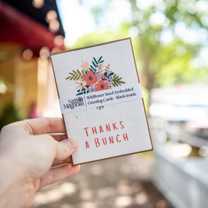 Hand holding a "Thanks a Bunch" plantable seed card with wildflower seeds.