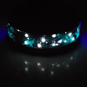 Glowing memorial ring with embedded ashes, black onyx mica, and star constellations on a black ceramic band.