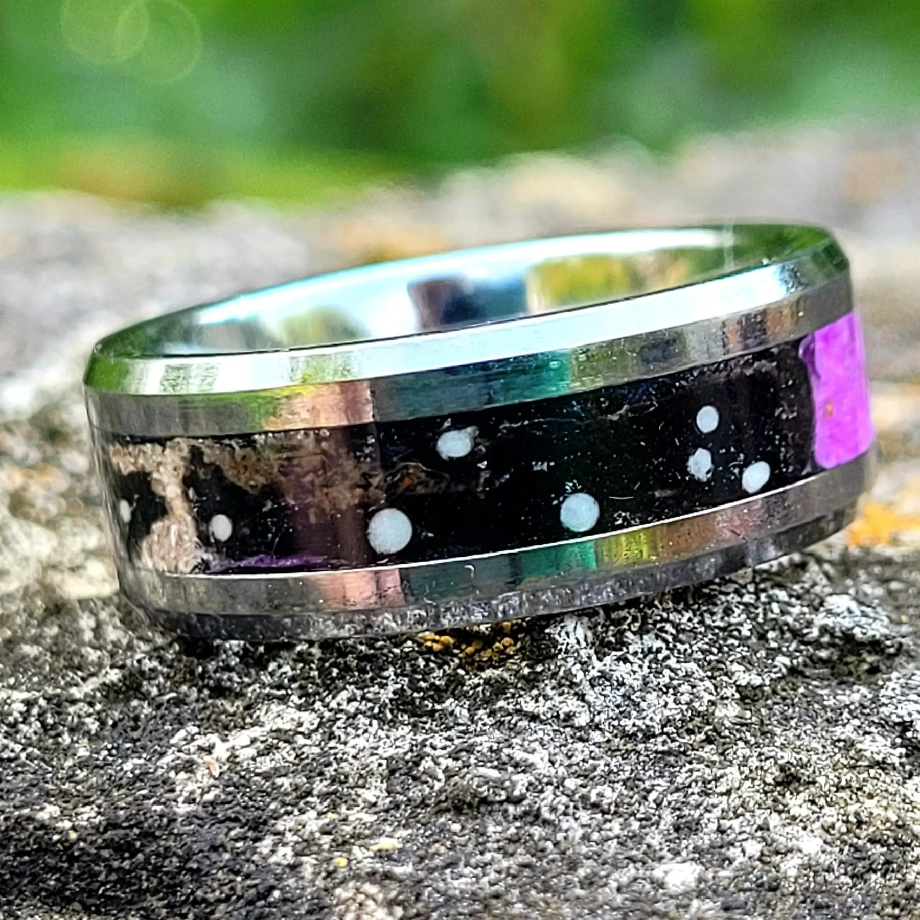 Constellation memorial ring made with ashes, black onyx, purple glow and white constellation details in a silver band on a rock.
