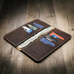Brown leather long wallet with card slots and cash pockets on a wooden surface.