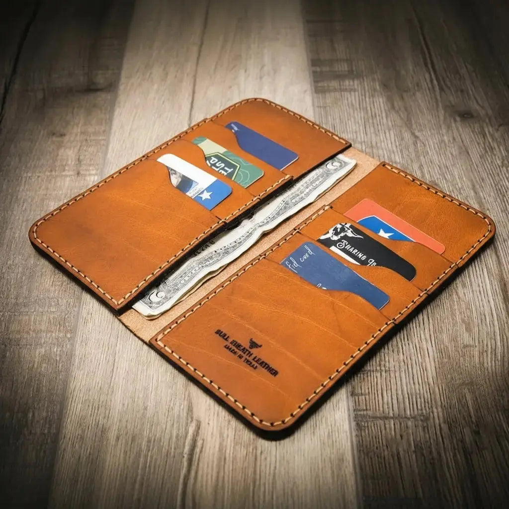 Tan leather long wallet open with credit cards and US dollar bills visible.