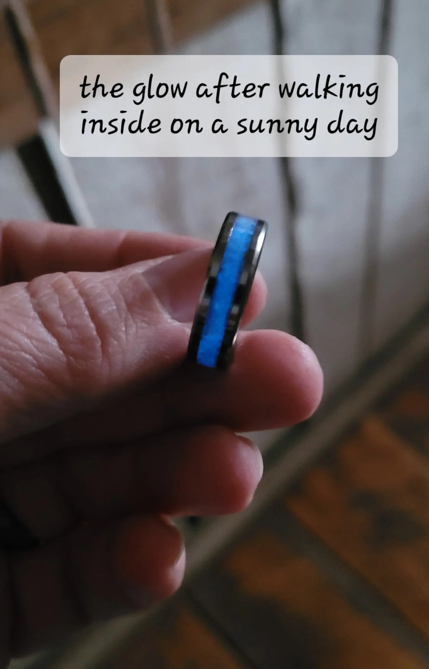 Hand holding a black ring with a blue glowing center inlay.