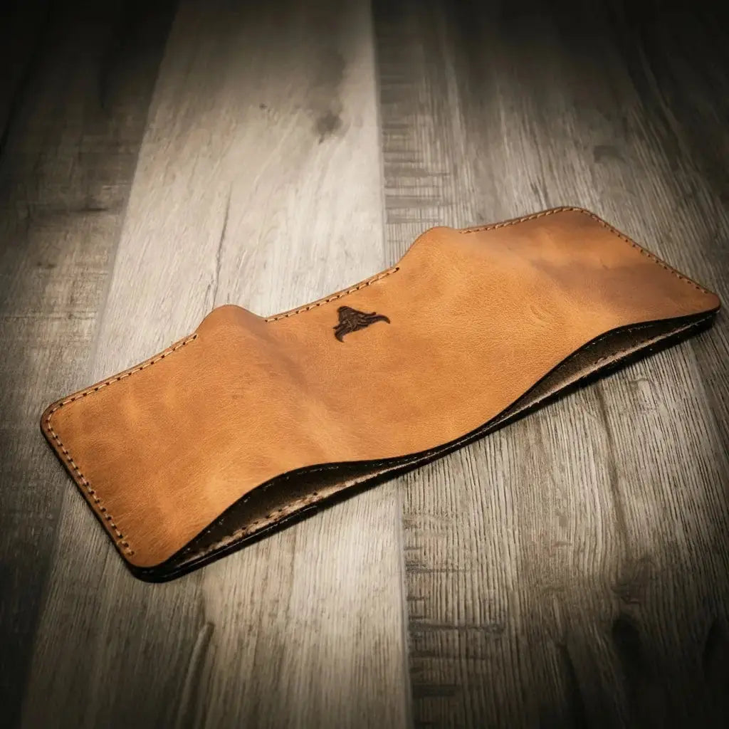 Brown leather trifold wallet with stitching and a dark logo on a wooden background.