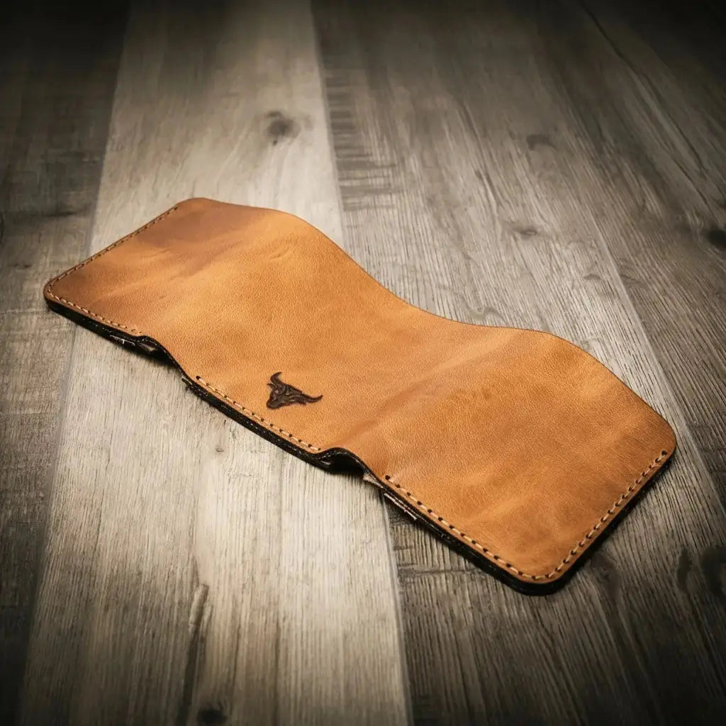 Brown leather trifold wallet with a bull logo on a wood background.