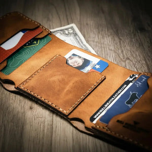 Brown leather trifold wallet holding credit cards and cash.