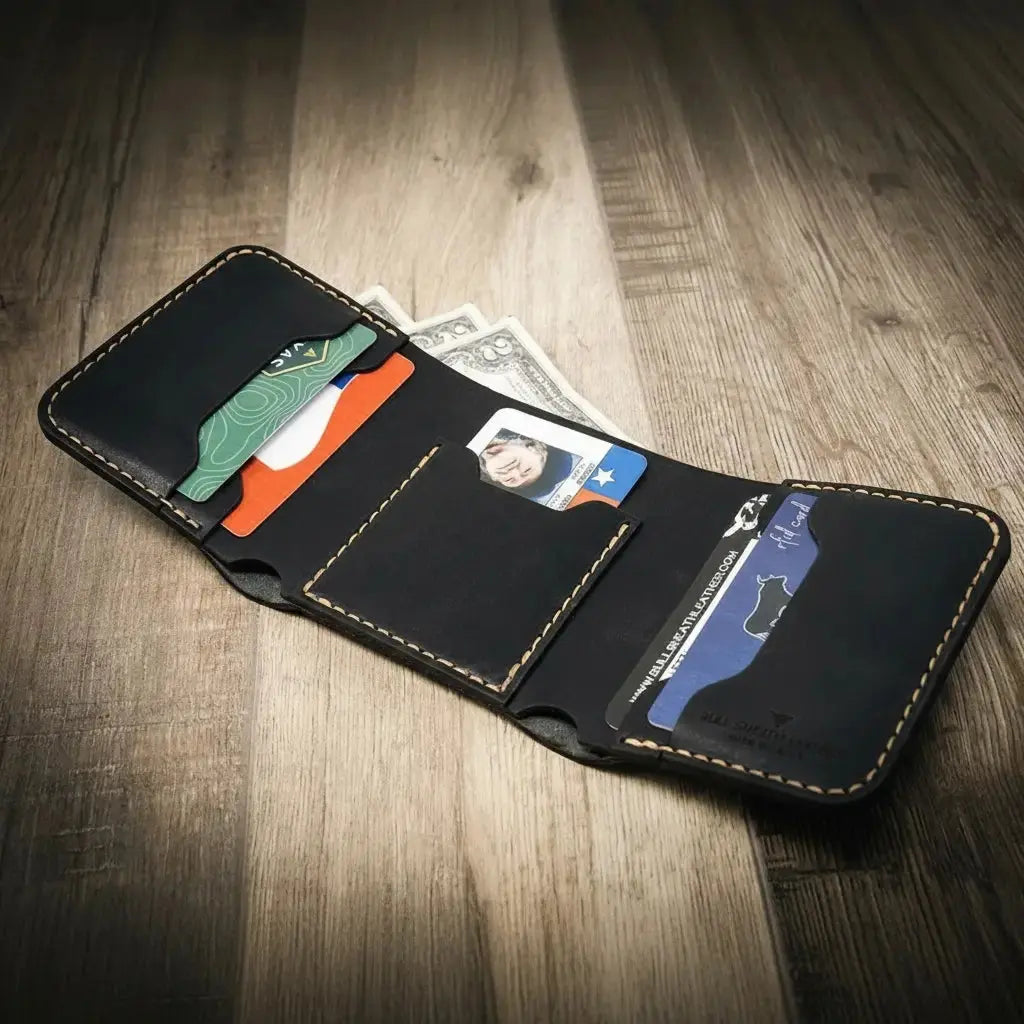 Black leather trifold wallet with cards and cash on a wooden surface.
