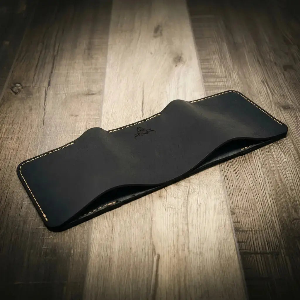 Black leather trifold wallet with white stitching on a wooden background.
