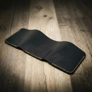Dark navy leather trifold wallet with embossed logo and contrasting stitching on wood.