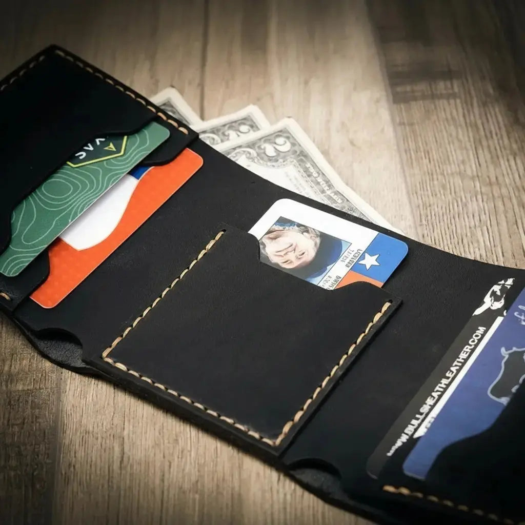 Black leather trifold wallet with credit cards and US dollar bills.