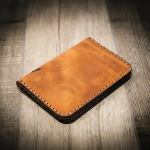 Brown full-grain leather vertical wallet with stitched edges on a wooden background.