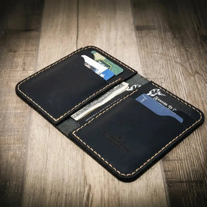 Black leather vertical wallet with card slots and cash pockets on a wood grain background.