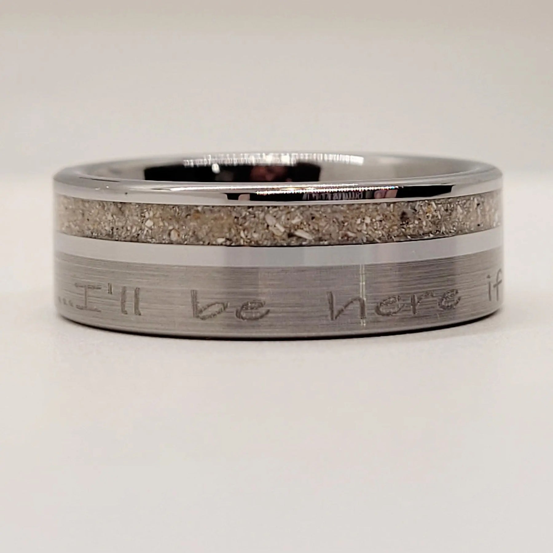 Tungsten ring with engraved text and sand inlay.